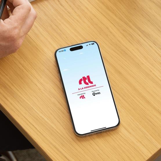 Un téléphone affichant l’application RTL à la demande, avec le véhicule qui arrive en arrière-plan